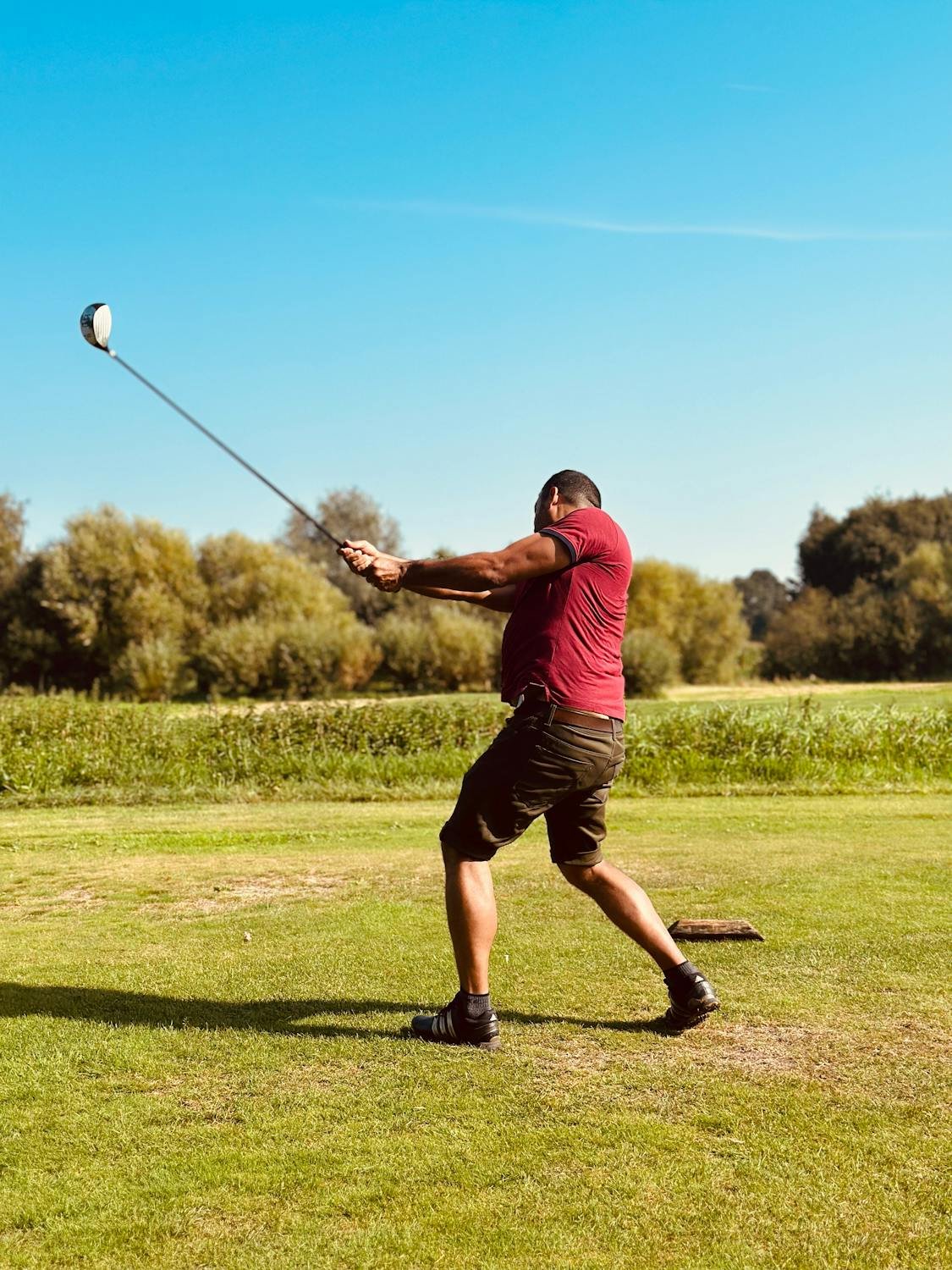 magnetic cigar clip golf - man swinging golf club on lush green course action shot